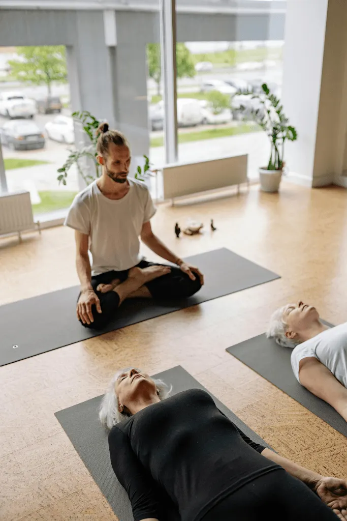 Yoga teacher guiding a student resting in savasana at the end of a class